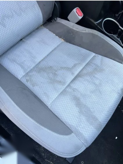 Stained, dusty cloth car seat before a deep interior clean
