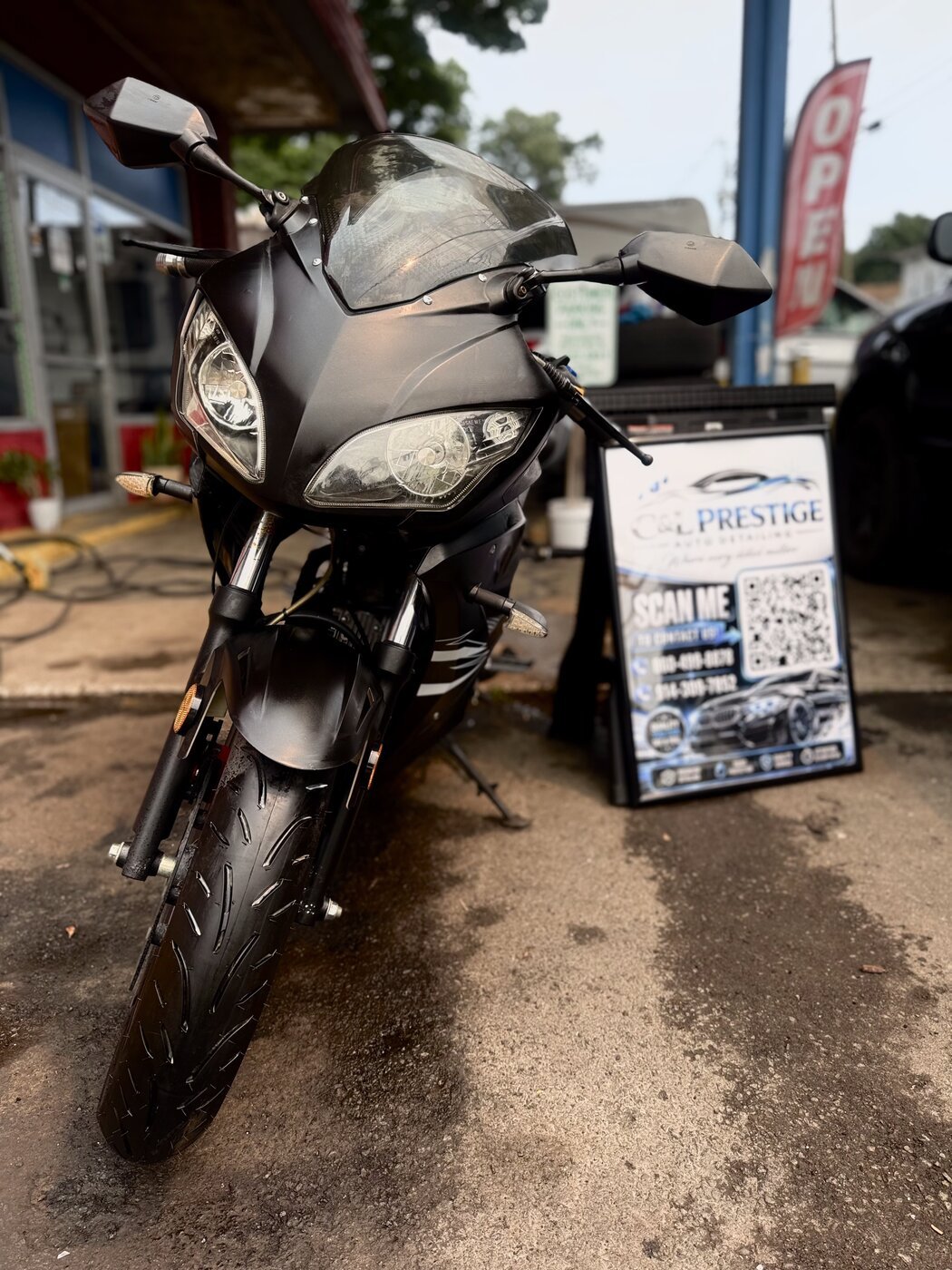 Detailed motorcycle parked next to the C&L Prestige sign board